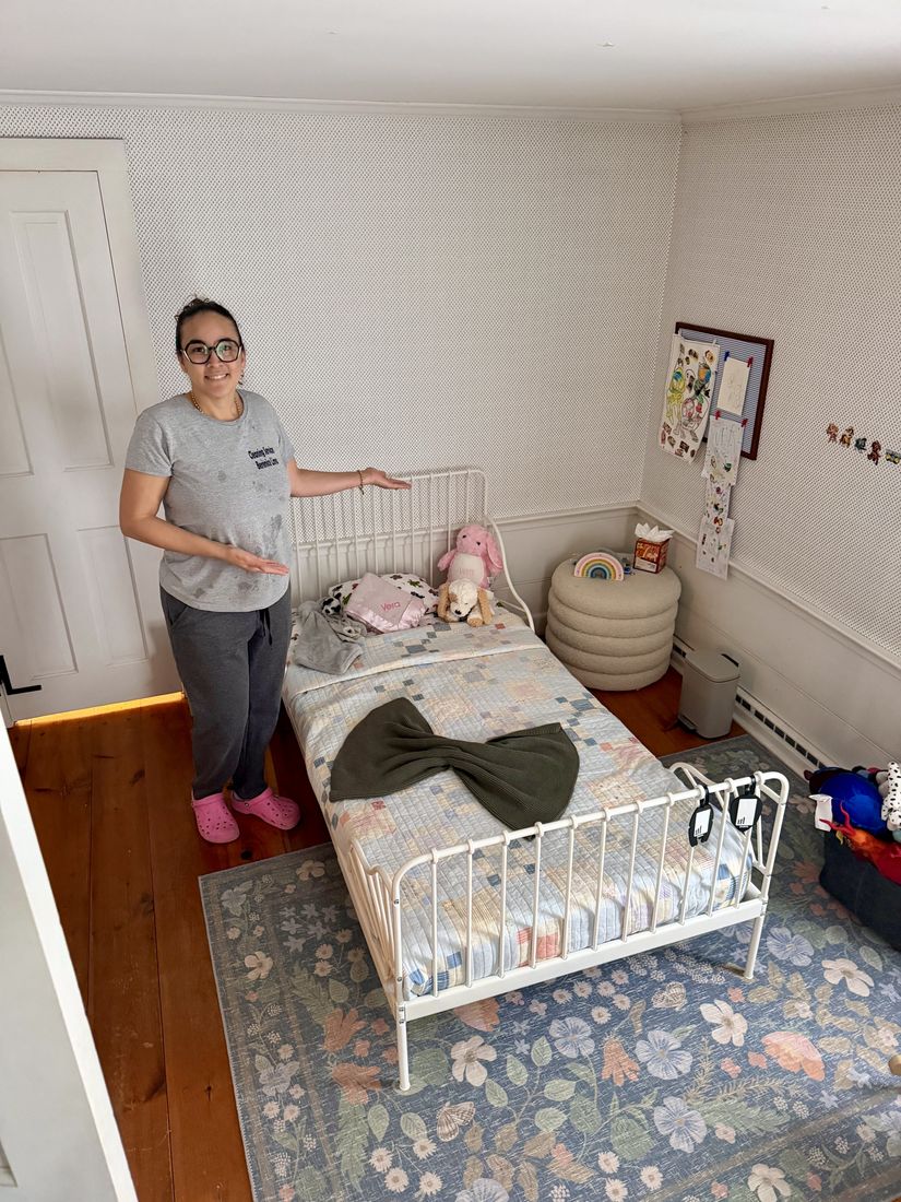 Berenice smiling and gesturing to a freshly made child's bedroom